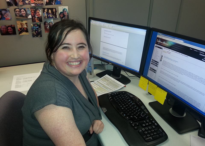 A woman sitting at a desk smiling