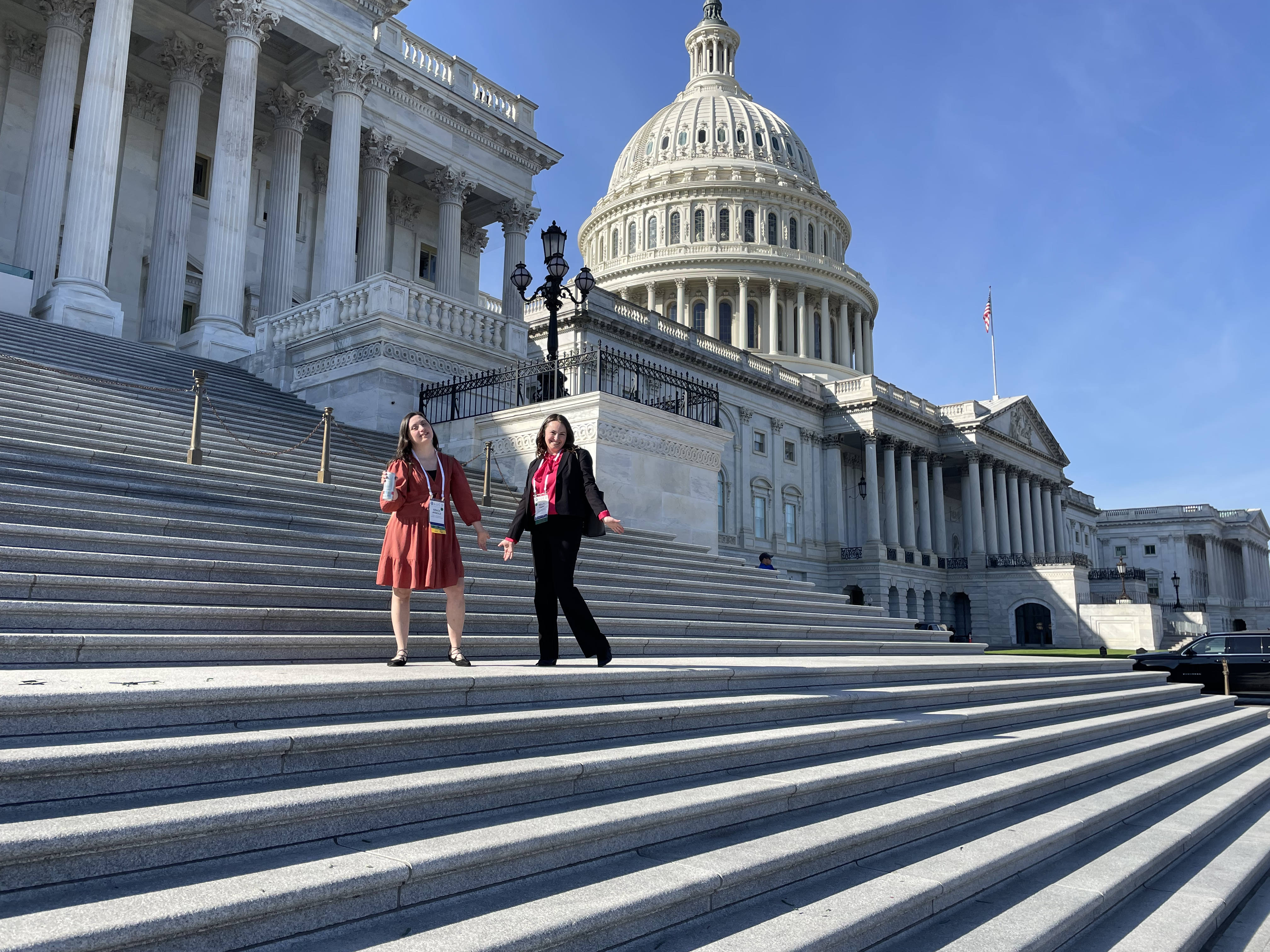 Two women on the steps of the US Capitol on a sunny, clear day.