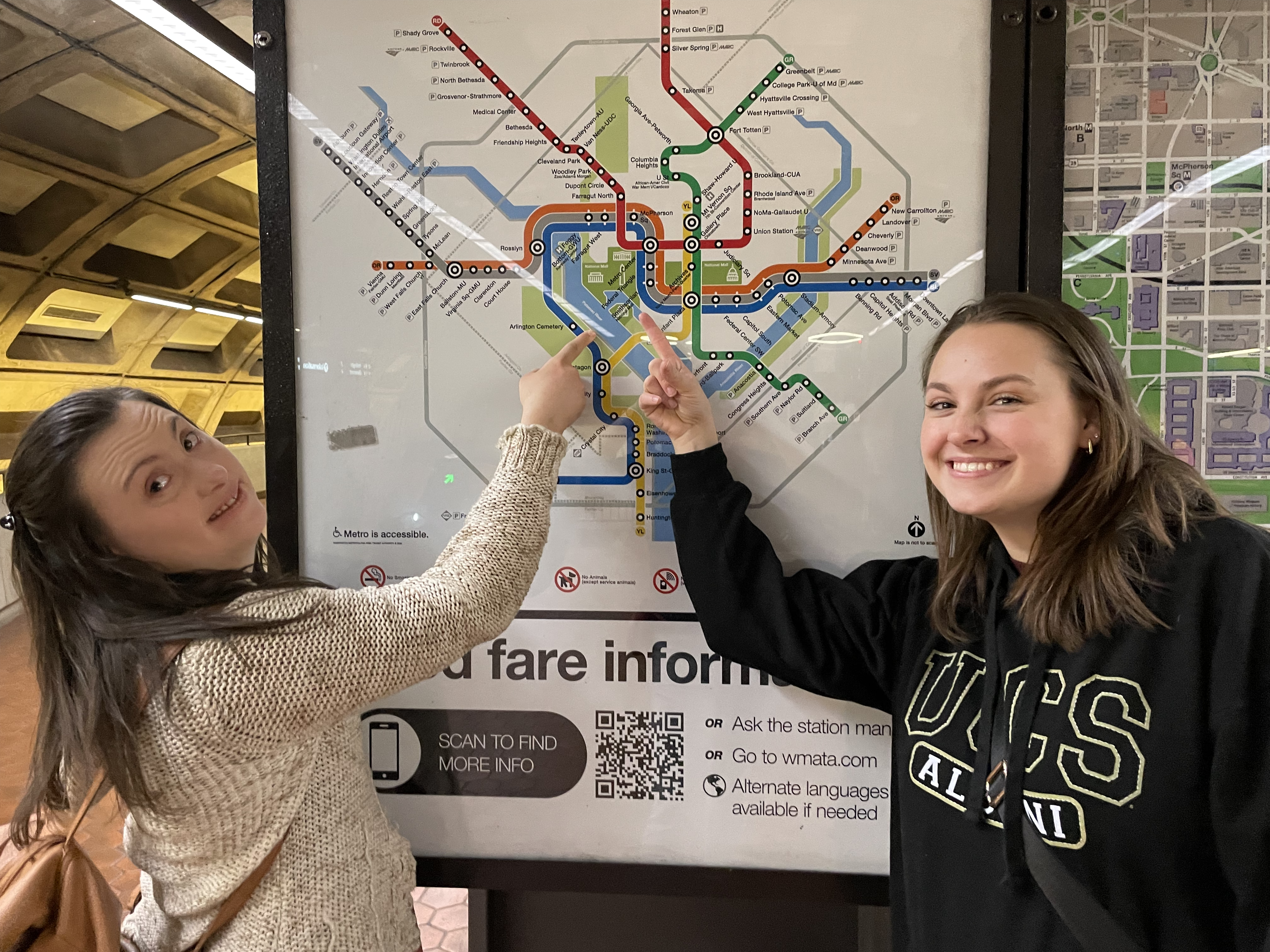 Two women smiling, pointing to a Washington DC Metro map.