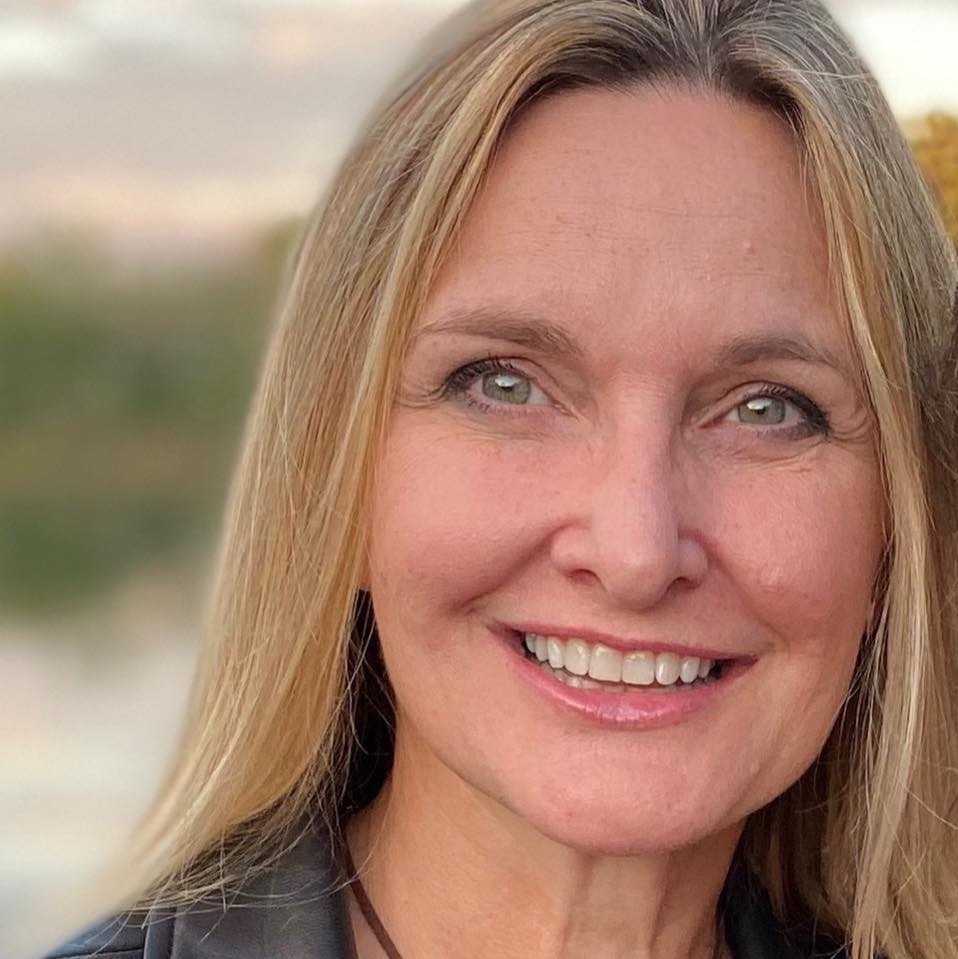 Meg Grigal is a white woman with long blond hair and blue eyes, smiling and looking into the camera