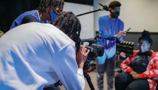 Four black students work together on a film production set