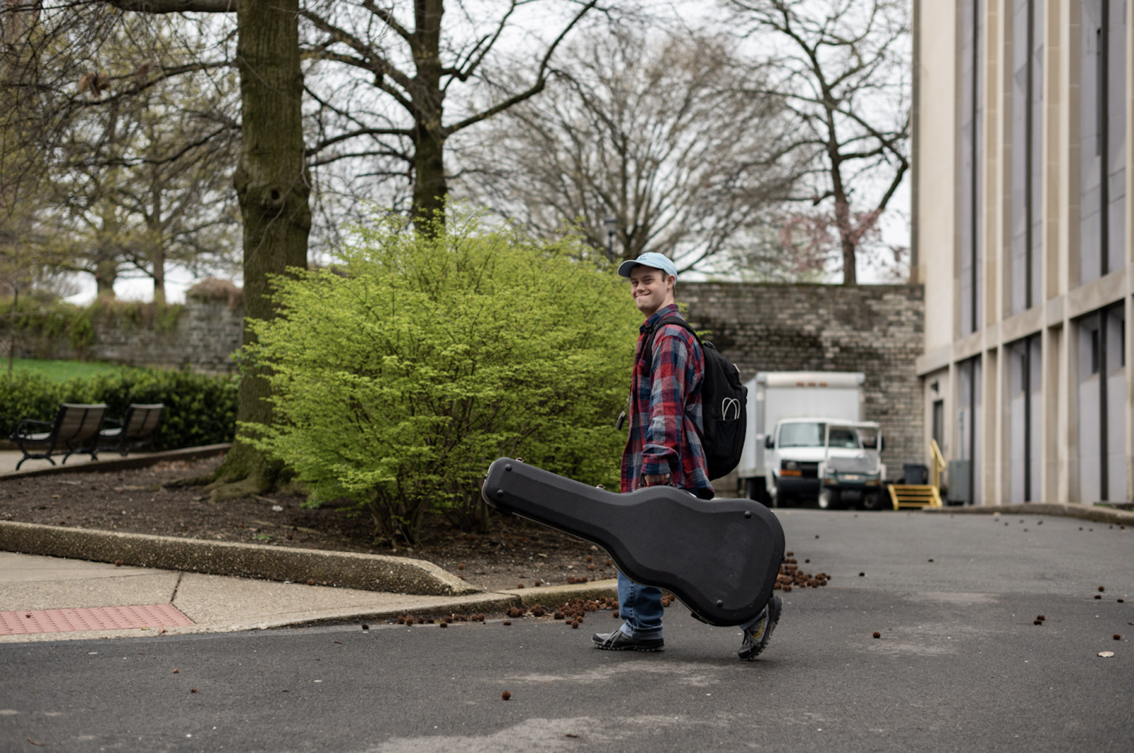 Student carries music instrument case across campus