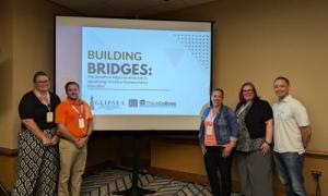 Two people stand to the left of a screen and three people stand to the right. On the screen a slide is projected that says “Building Bridges: The Growth of Regional Alliances in Advancing Inclusive Postsecondary Education” along with the GLIPSEA & ICI Think College logos