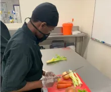 young student with disabilities chopping vegetables in an industrial kitchen