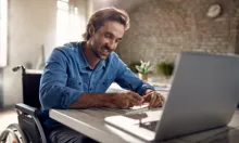 man in wheelchair typing on a laptop