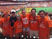 a group of Syracuse University students, all dressed in SU orange, at a football game.