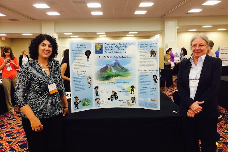 Two women standing next to a display for the Future Quest Island project, smiling.