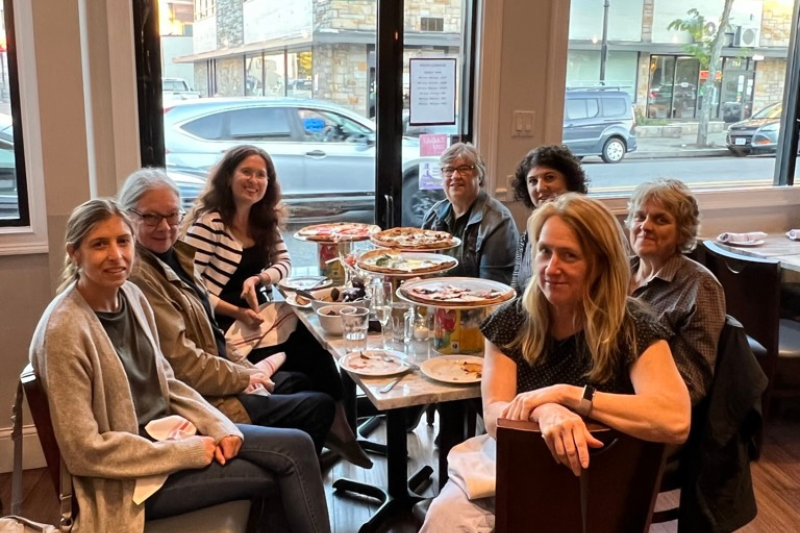 Colleagues sitting around a table eating pizza