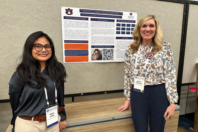 Two women stand in front of a poster presentation.