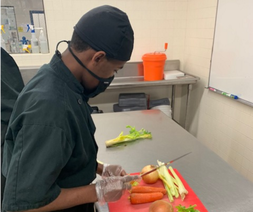 young student with disabilities chopping vegetables in an industrial kitchen