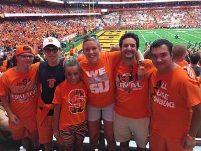 a group of Syracuse University students, all dressed in SU orange, at a football game.